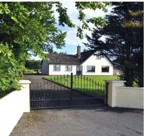 a white house with a gate in front of it at Islands View in Wexford