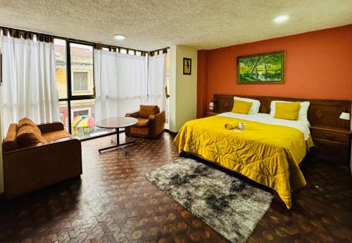 a bedroom with a yellow bed and a chair at Hotel Las Americas in Cuenca