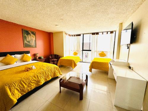 een slaapkamer met oranje muren en een bed met gele lakens bij Hotel Las Americas in Cuenca