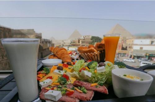 einen Tisch mit einem Teller mit Speisen und Getränken in der Unterkunft AliBaba Pyramids View Inn in Kairo