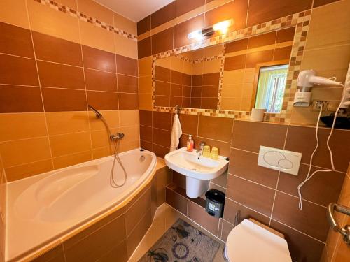 a bathroom with a tub and a sink and a toilet at Apartmány Slavkov - Dolný Smokovec in Vysoke Tatry - Dolny Smokovec