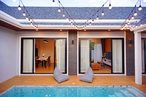 a house with a swimming pool in front of a house at Nattarin Pool Villa Pattaya-Na Chom Thian in Ban Map Fakthong