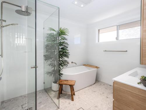 a bathroom with a bath tub and a potted plant at Coastal Home, 500m Walk to Hospital with Ocean Views in Kingscliff