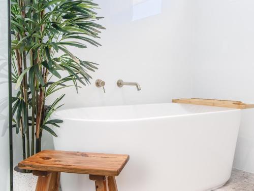 a bathtub with a wooden stool next to a plant at Coastal Home, 500m Walk to Hospital with Ocean Views in Kingscliff