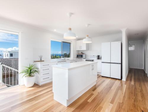 a kitchen with white cabinets and a large window at Coastal Home, 500m Walk to Hospital with Ocean Views in Kingscliff