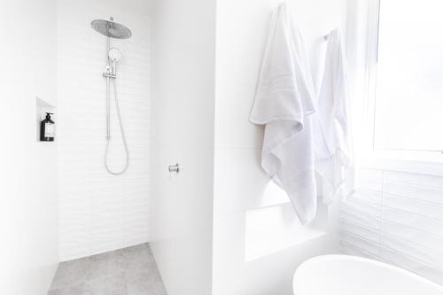 a white bathroom with a shower and a toilet at Ocean Escape, Pet Friendly in Ocean Grove