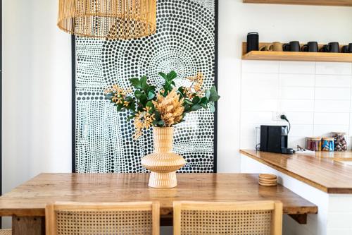 a dining room table with a vase with flowers at Ocean Escape, Pet Friendly in Ocean Grove