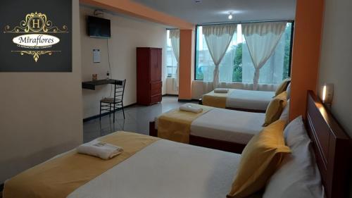 a hotel room with two beds and a window at Hotel Miraflores in Ibarra
