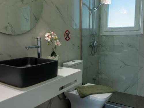 a bathroom with a black sink and a toilet at RHOMBUS by the sea in Paleo Tsifliki