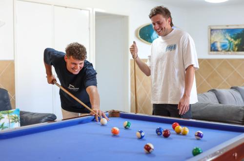 two men playing a game of pool in a room at Motel Sunshine Coast in Caloundra