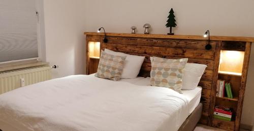 ein Schlafzimmer mit einem weißen Bett mit einem hölzernen Kopfteil in der Unterkunft Talstation in Braunlage