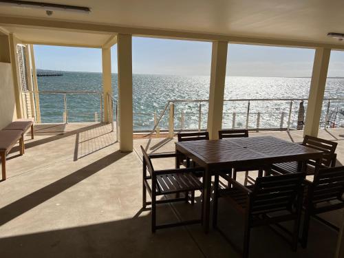 einen Tisch und Stühle auf einem Balkon mit Meerblick in der Unterkunft Beachside & Jetty View Apartment 2 -Skippers Apartment in Streaky Bay