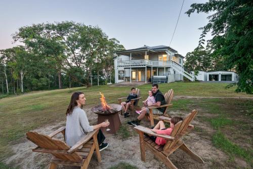 a group of people sitting around a fire pit in front of a house at Lakeview Cottage in Mooloolah Valley in Mooloolah