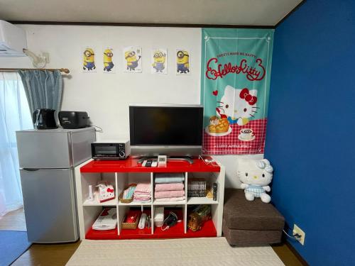 a room with a red table with a tv and a refrigerator at 無料駐車場付き usjまで車で約10分 HOSITOSORA梅香 in Osaka