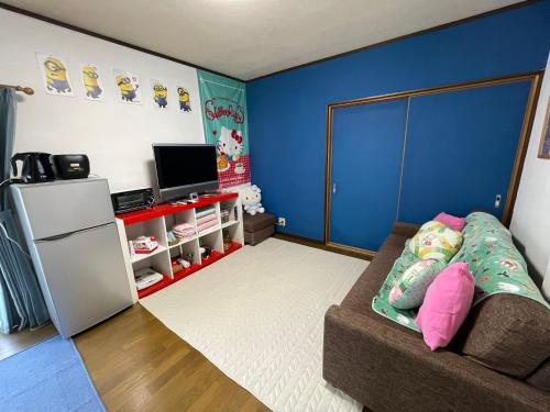 a living room with a couch and a refrigerator at 無料駐車場付き usjまで車で約10分 HOSITOSORA梅香 in Osaka