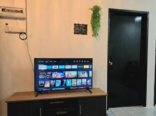 a flat screen tv sitting on a table next to a door at Trio Homestay at Tanah Merah in Tanah Merah