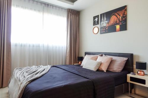 a bedroom with a bed with blue sheets and a window at Water Park Condominium in Pattaya South