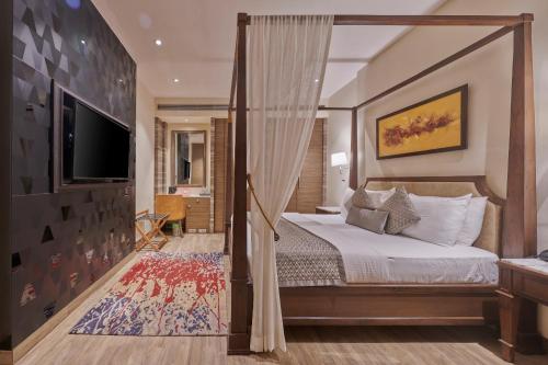 a bedroom with a canopy bed and a television at Residency Hotel Fort in Mumbai