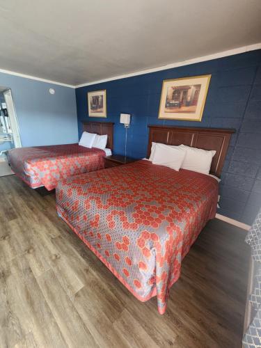 2 camas en una habitación de hotel con paredes azules en Guest House Motel en Carthage