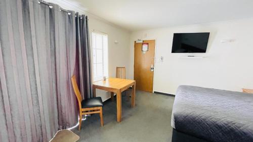 una camera da letto con scrivania, letto e tavolo di City Suites a Tauranga