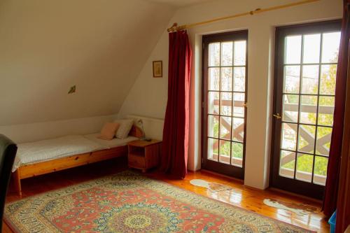 a bedroom with a bed and two large windows at Pine Grove Villa in Gödöllő