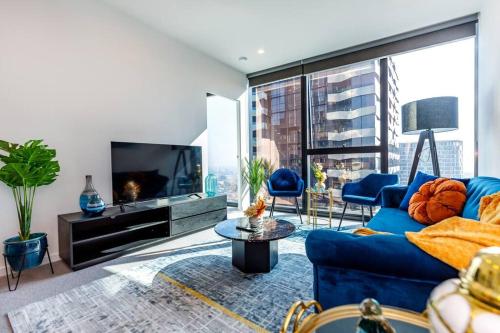 un soggiorno con un divano blu e una TV di Sky High 180 Panoramic Views-Prime CBD,Pool & Gym a Melbourne