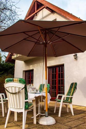 a table with chairs and an umbrella in front of a house at Pine Grove Villa in Gödöllő