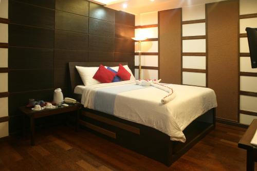 a bedroom with a large bed with red pillows at Ripple Beach Inn in Hulhumale