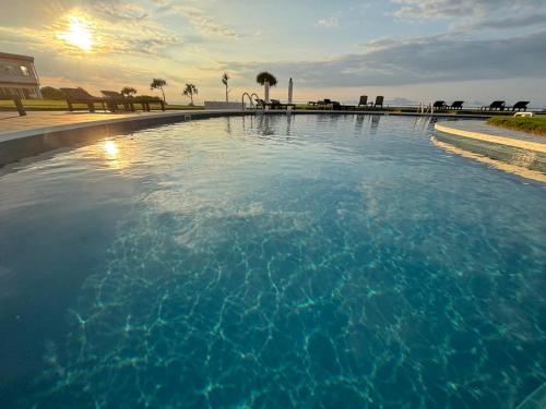 a large pool of blue water with palm trees in the background at EN RESORT Kumejima EEF Beach Hotel in Kumejima