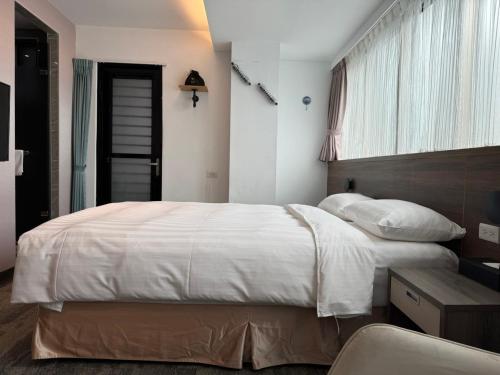sypialnia z dużym białym łóżkiem i oknem w obiekcie RF Hotel – Linsen w Tajpej