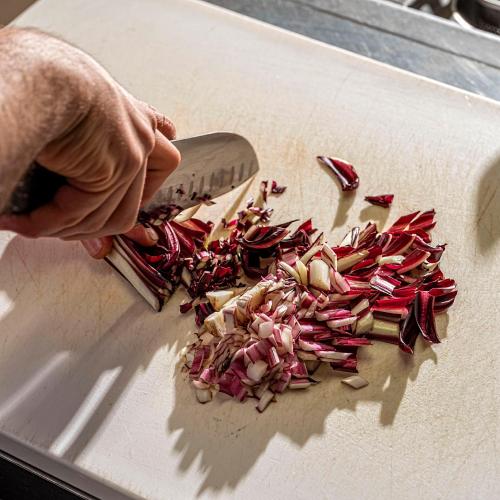 a person cutting up onions on a cutting board with a knife at Il Castagneto Hotel in Melfi