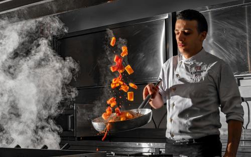 a man in a kitchen cooking food in a wok at Il Castagneto Hotel in Melfi