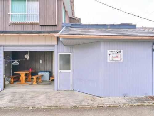 a blue building with a door and a picnic table at Kokoyui Guest House in Nachikatsuura