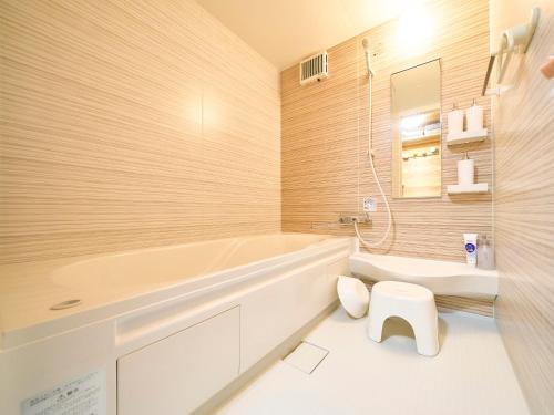 a bathroom with a tub and a toilet and a sink at Kokoyui Guest House in Nachikatsuura