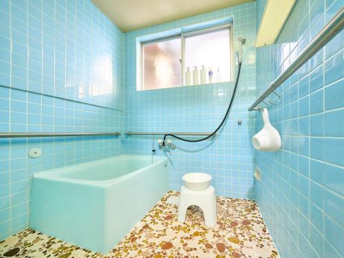 a blue bathroom with a tub and a toilet at Kokoyui Guest House in Nachikatsuura