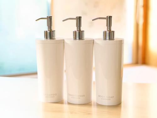 three white bottles sitting on top of a table at Kokoyui Guest House in Nachikatsuura