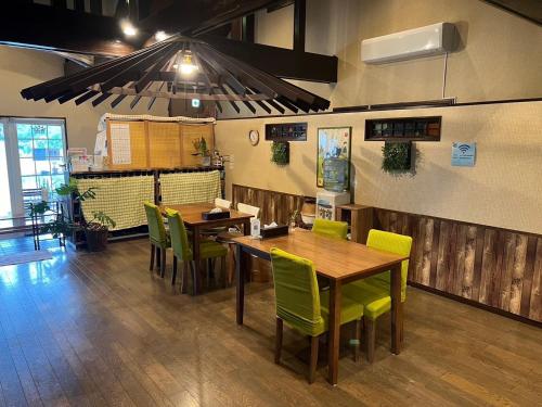 un restaurante con mesas de madera y sillas verdes en 百合ヶ浜ビーチハウス, en Furusato