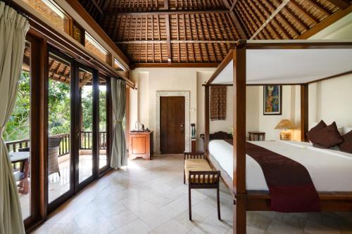 a bedroom with a bed and a balcony at Svarga Bebek Villas in Ubud