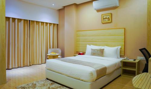 a hotel room with a bed and a chair at Grand Vistana in Dhaka