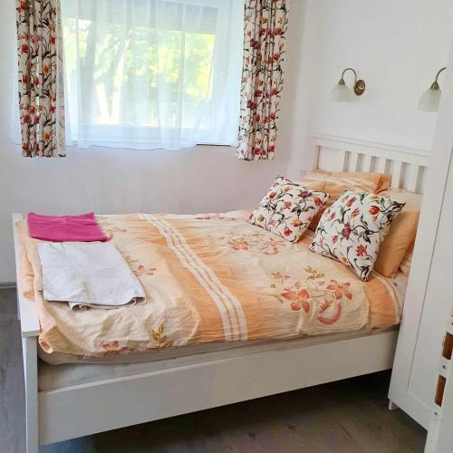 1 cama en un dormitorio con ventana y almohadas en ARANY13 Apartmanház - Mówimy po polsku!, en Bogács
