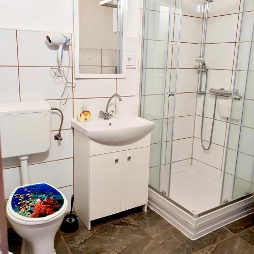 a bathroom with a toilet and a sink and a shower at ARANY13 Apartmanház - Mówimy po polsku! in Bogács