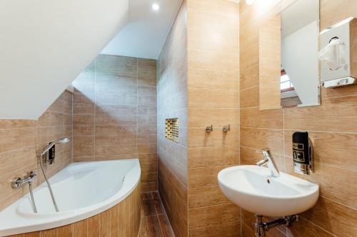 a bathroom with a bath tub and a sink at Wellness rezort Jánošíkov dvor in Zázrivá