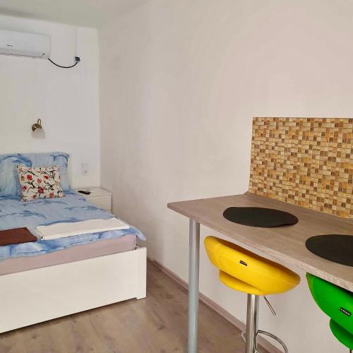 a bedroom with a bed and a desk with a yellow chair at ARANY13 Apartmanház - Mówimy po polsku! in Bogács