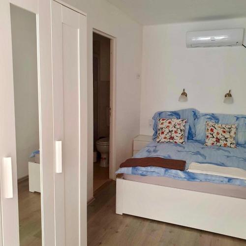 a bedroom with a bed with blue sheets and a toilet at ARANY13 Apartmanház - Mówimy po polsku! in Bogács