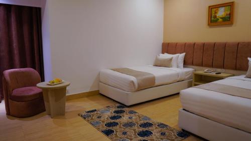 a hotel room with two beds and a chair at Grand Vistana in Dhaka