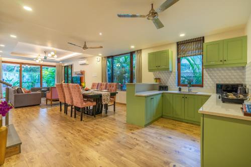 a kitchen and living room with green cabinets and a table at ELIVAAS 3 BHK with Pvt Pool - Azalea in Siolim