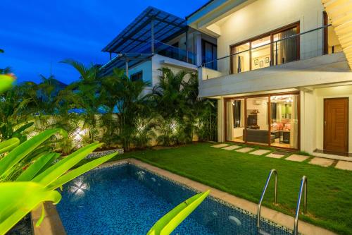 a villa with a swimming pool in front of a house at ELIVAAS 3 BHK with Pvt Pool - Azalea in Siolim