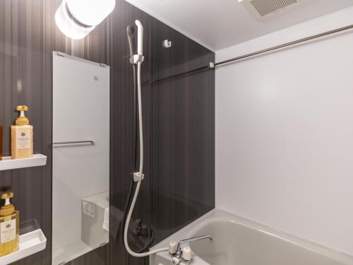 a shower with a shower head in a bathroom at Tabist GROOVE KYOTO OKOSHIYASU in Kyoto