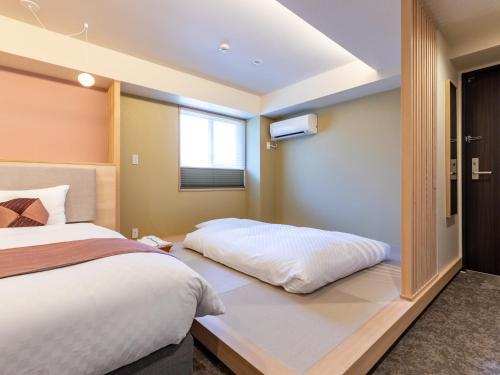 a bedroom with a large bed and a window at Tabist GROOVE KYOTO OKOSHIYASU in Kyoto