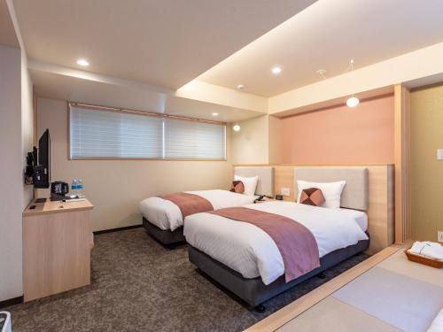 a bedroom with two beds and a television at Tabist GROOVE KYOTO OKOSHIYASU in Kyoto